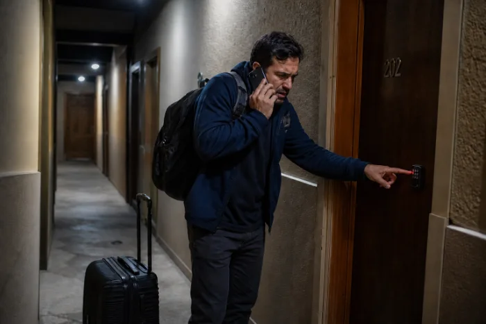 Hóspede perdido no corredor à noite, com mala, ligando pro anfitrião na porta errada